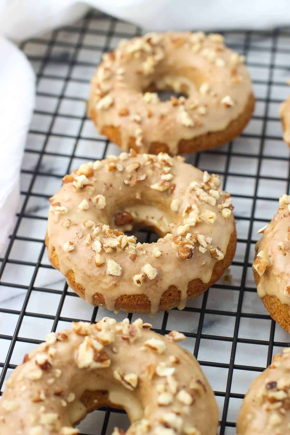 Glazed pumpkin donuts on a wire rack.