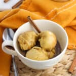 Four small scoops of pumpkin gelato in a large mug with espresso poured over top, all garnished with a whole cinnamon stick