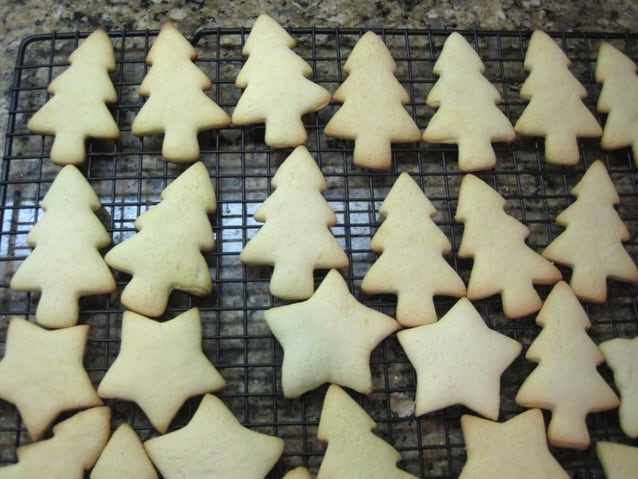 Un-iced tree and star shaped sugar cookies on a wire rack.