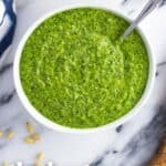 An overhead view of a bowl of pesto with recipe name text overlay.