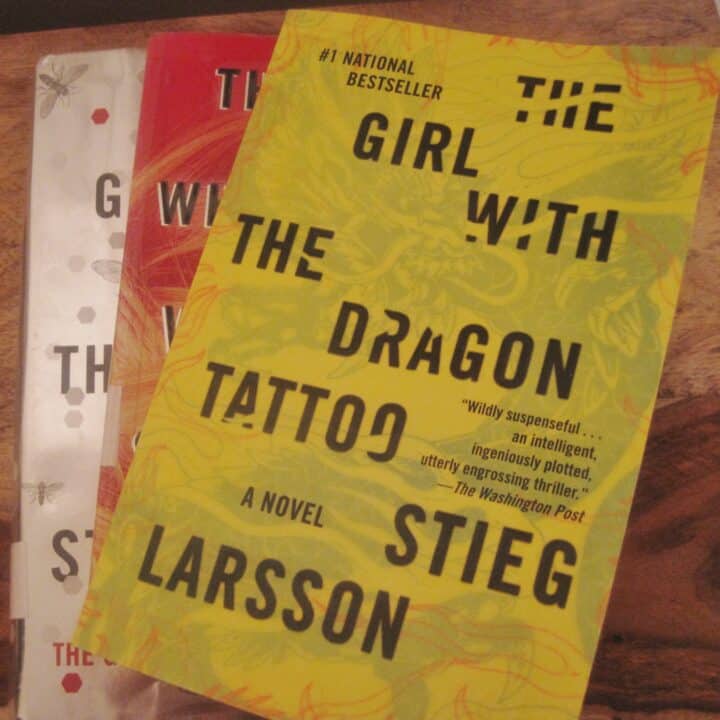 A stack of the three "The Girl with the Dragon Tattoo" series books on a wooden table.