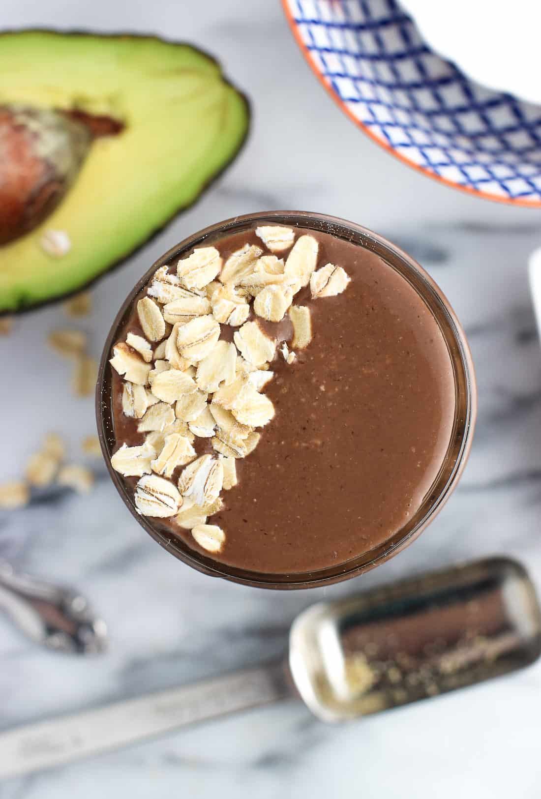 An overhead shot of a smoothie poured up to the brim of a glass jar topped with flaked oats.