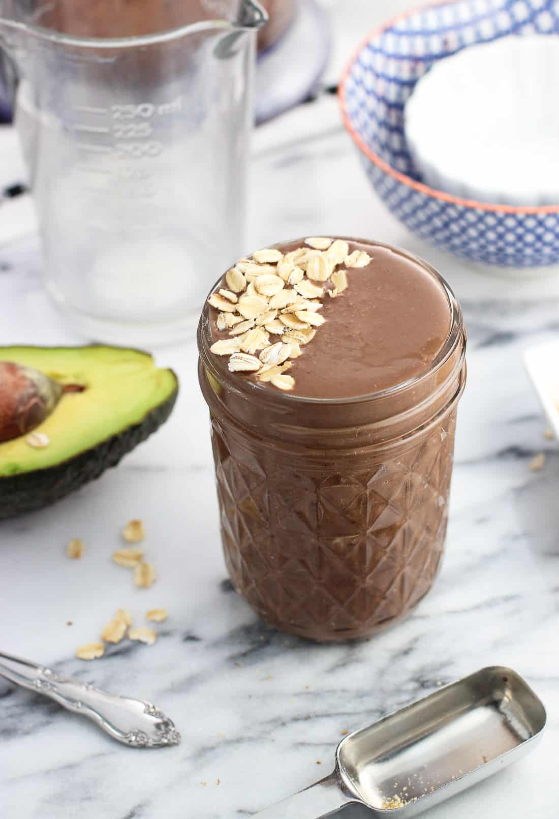 A side view of the smoothie in a glass jar on a marble board surrounded by ingredient remnants.