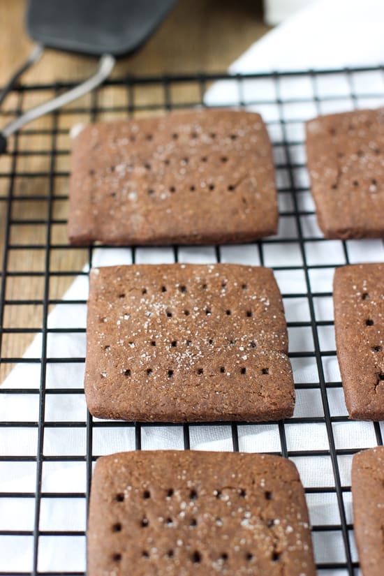 Chocolate graham crackers on a wire cooling rack next to a spatula.