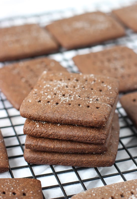 A stack of four graham crackers on a cooling rack surrounded by other crackes.