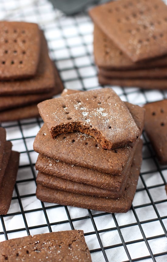 A stack of five chocolate graham crackers with a big bite taken out of the top cookie.