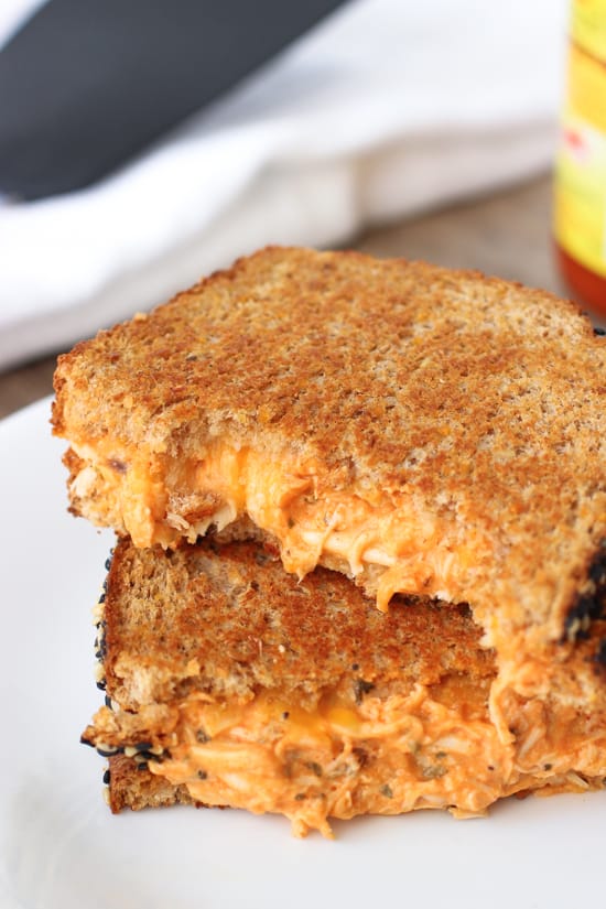 Two sides of a grilled cheese with creamy buffalo chicken filling stacked on one another on a plate.