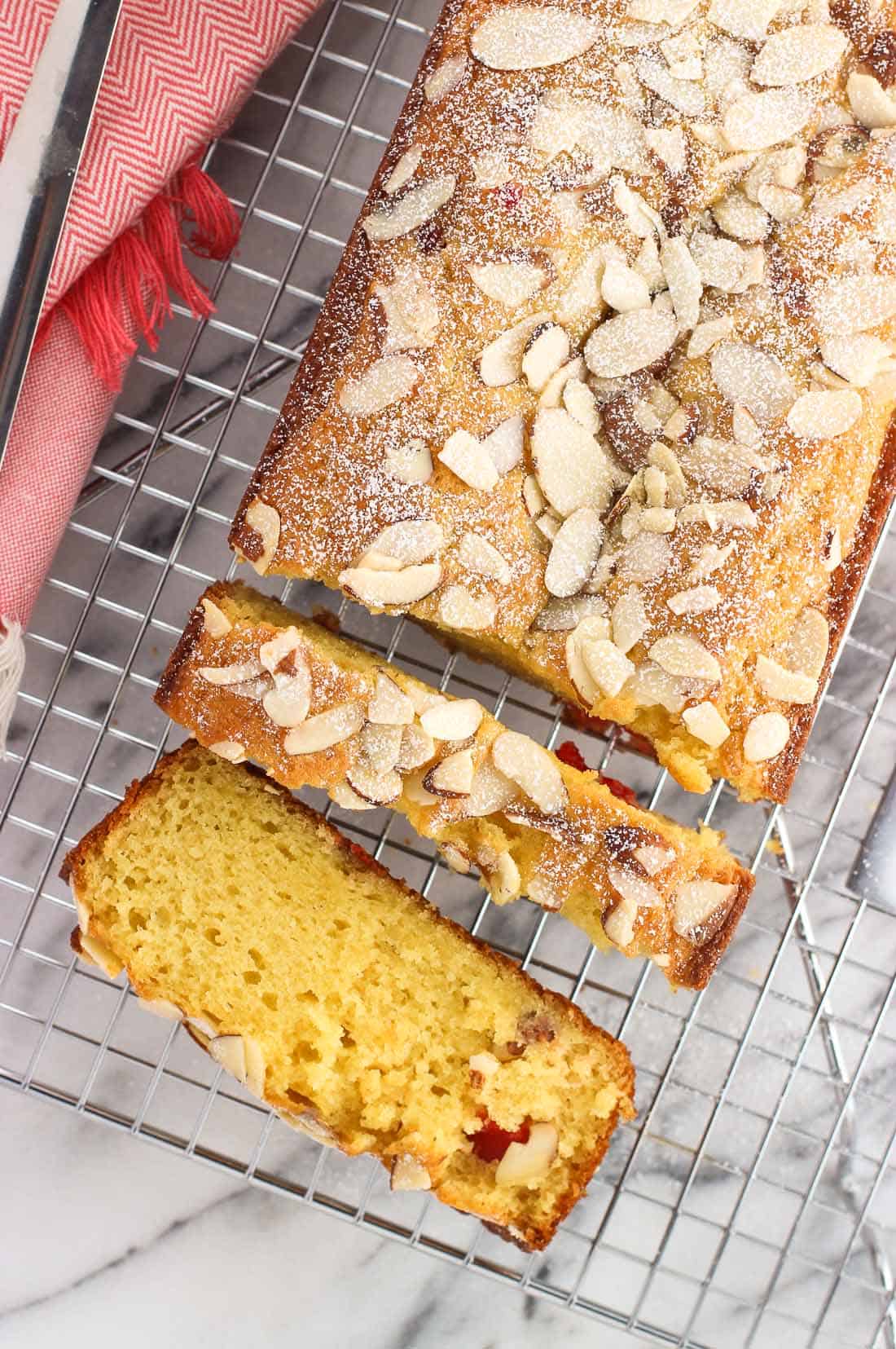 An overhead look of sliced cherry almond loaf cake on a wire rack