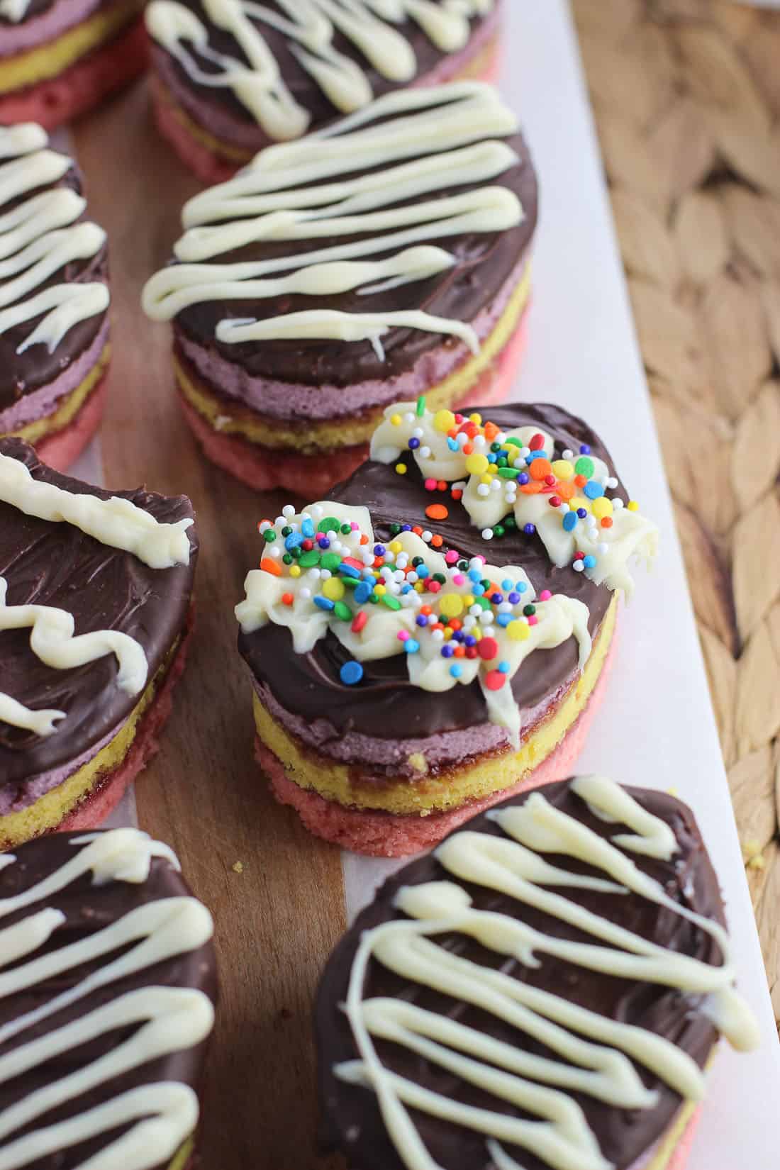 Easter egg rainbow cookies lined up on a marble serving tray.