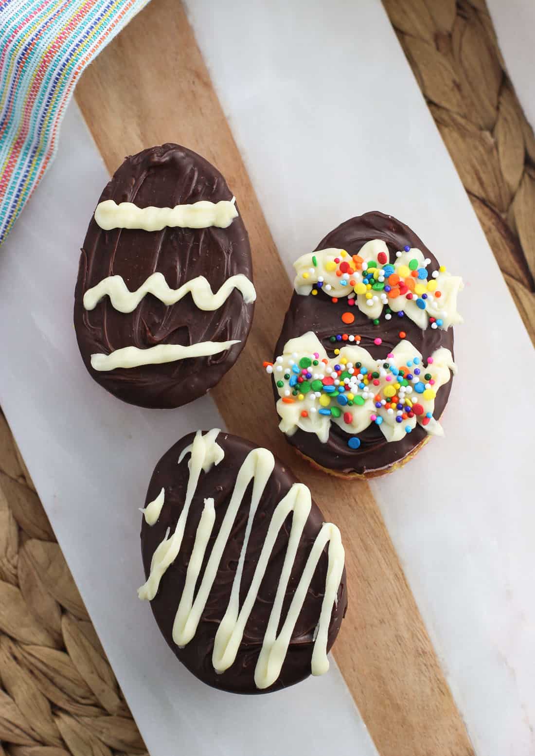 Easter egg decorated oval rainbow cookies on a marble tray.