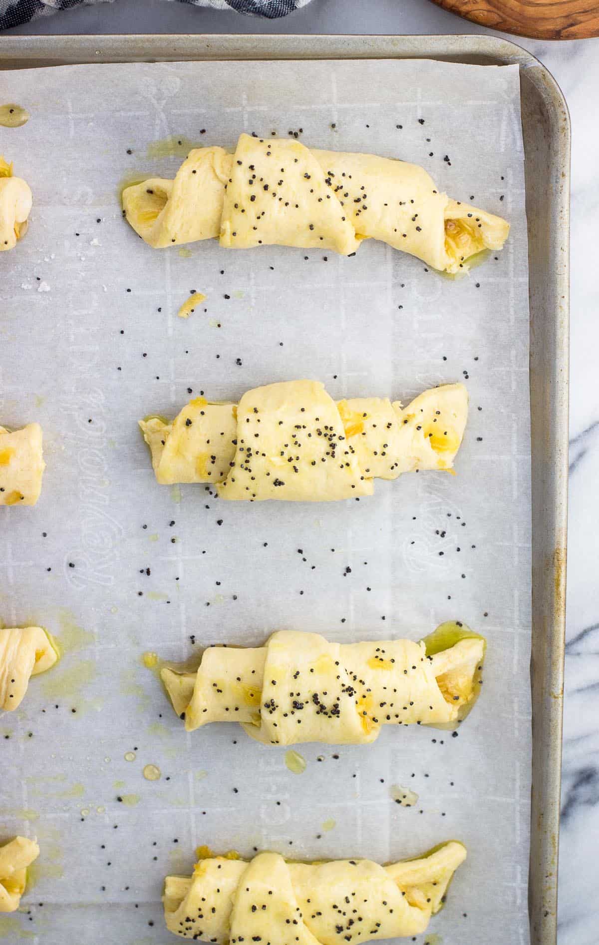 An overhead shot of onion crescent rolls on a sheet before being baked