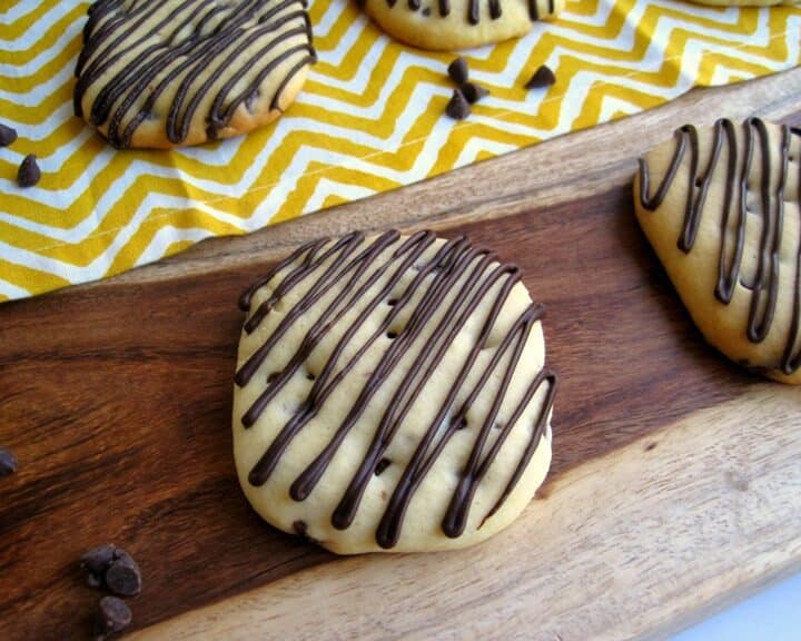 Iced orange chocolate chip sugar cookies on a wooden board.
