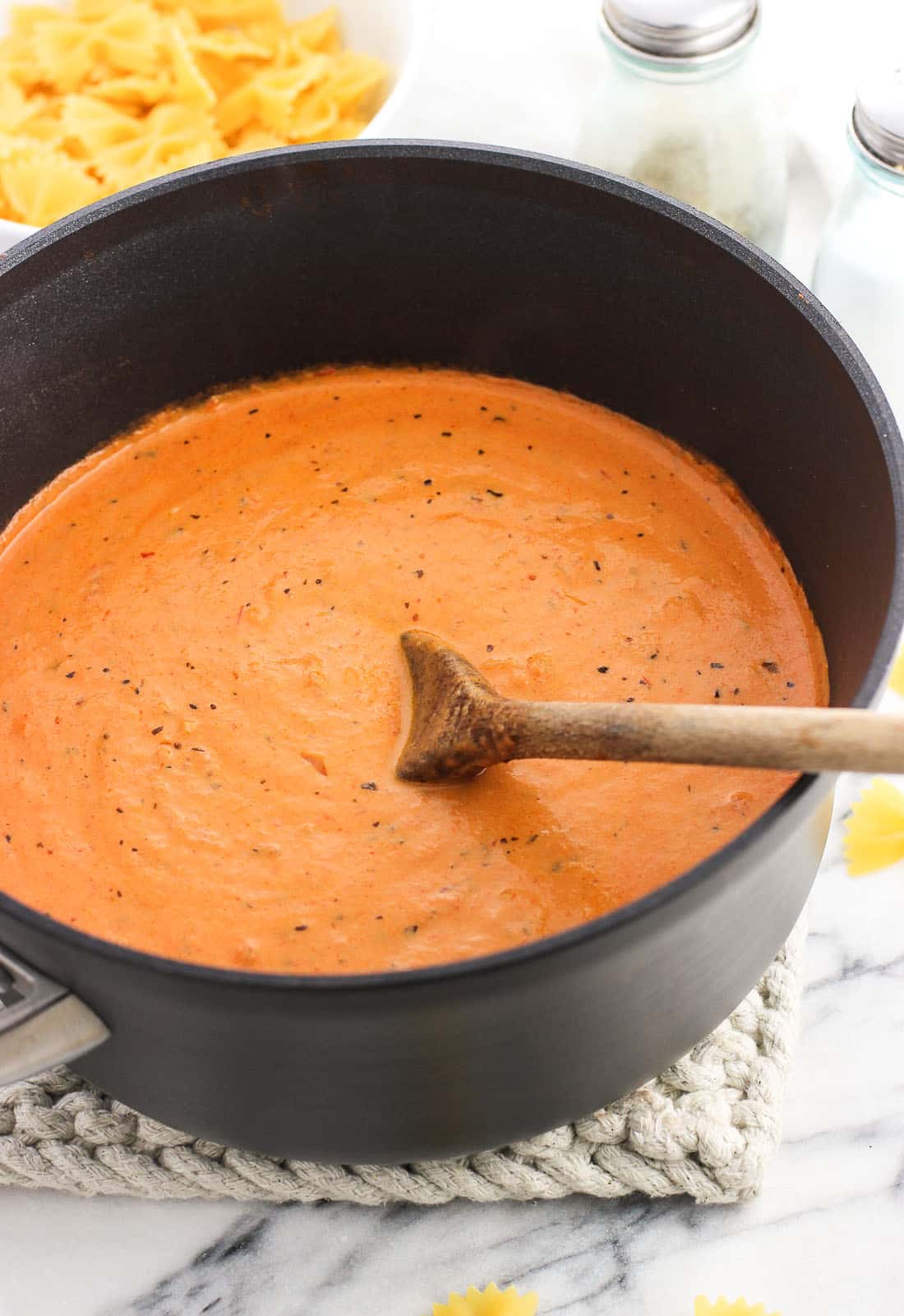 A sauce pan of vodka sauce with a wooden spoon in it.