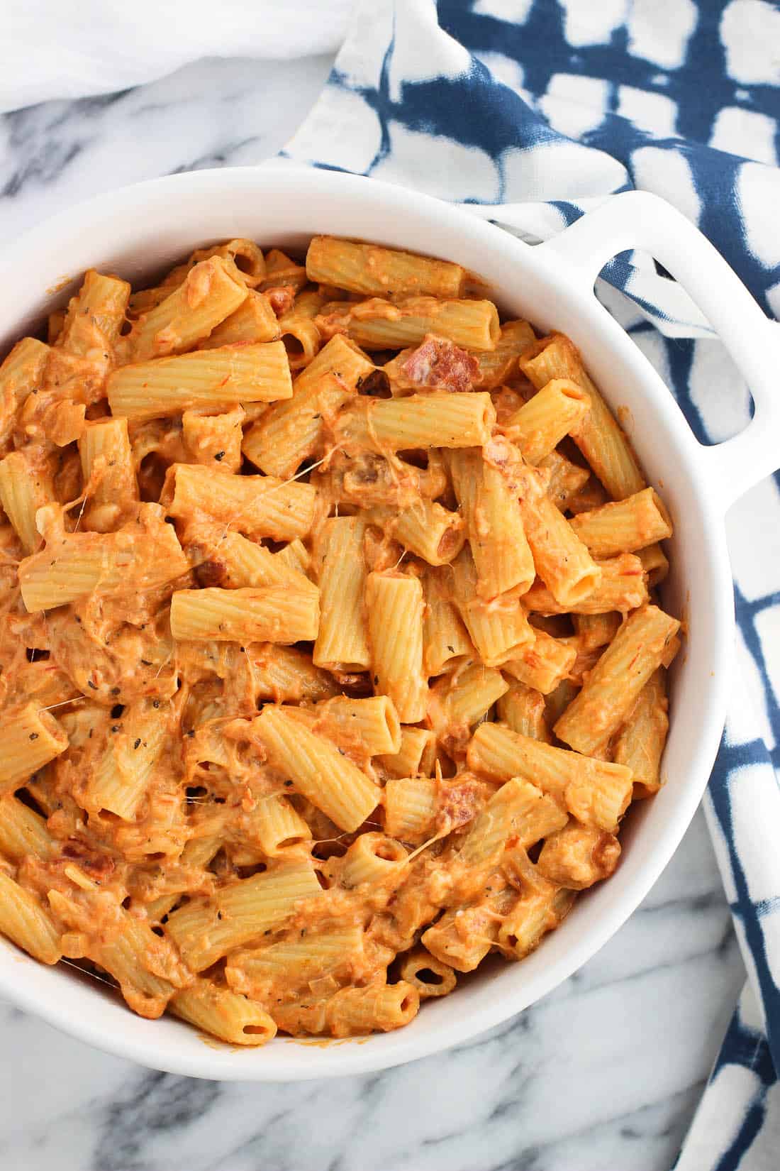 Cooked pasta, sauce, and cheese stirred together in a large dish before baking.