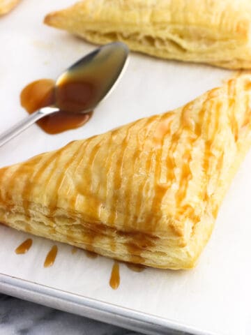 A caramel-drizzled turnover on a baking sheet.