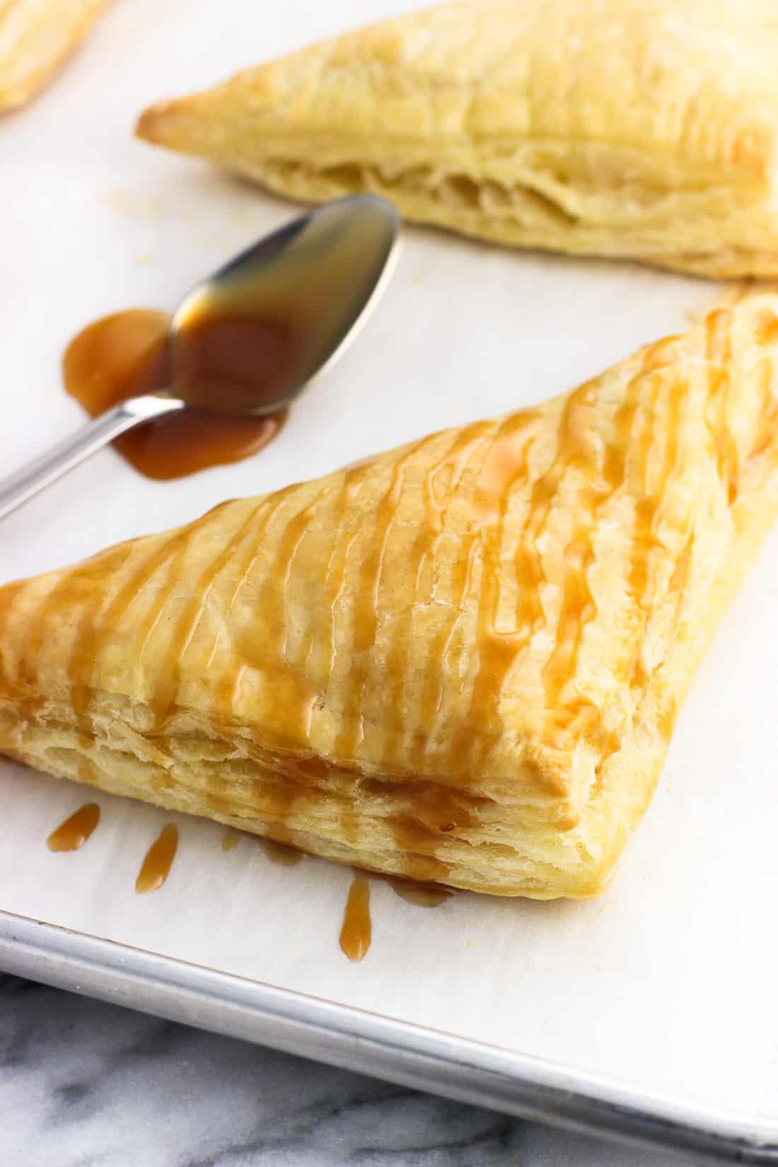 A caramel-drizzled turnover on a baking sheet.