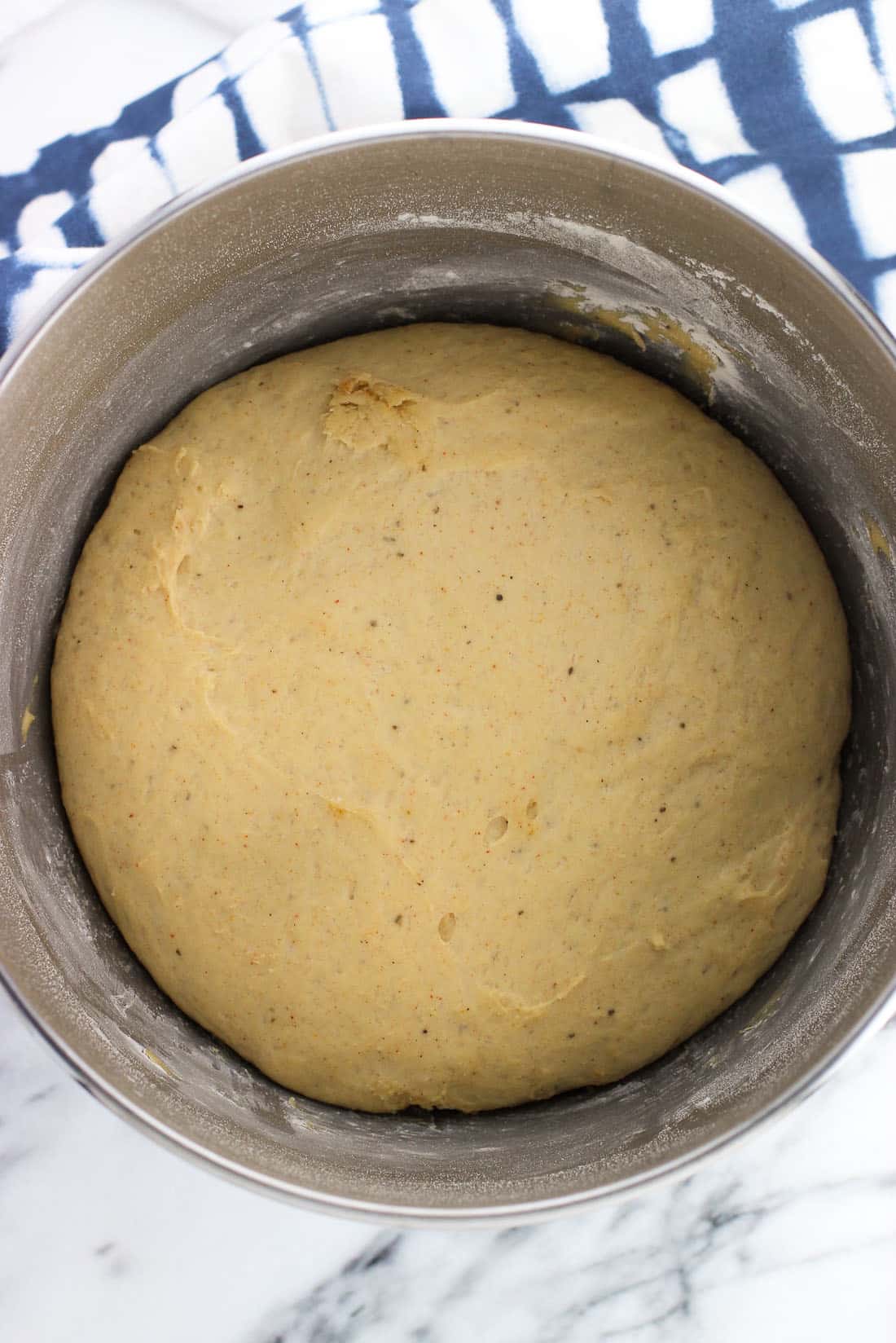An overhead picture of the risen dough in a metal stand mixer bowl