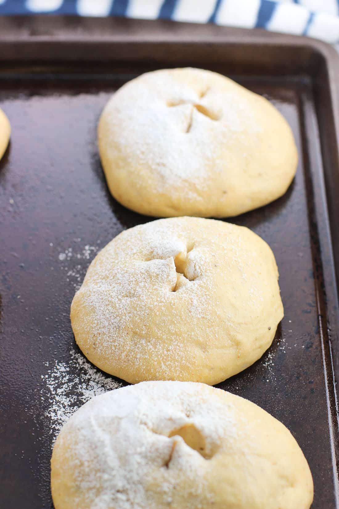 Rolls pre-bake on a greased baking sheet with an "x" snipped into the tops