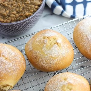 Rolls on a wire rack in front of a dish towel and a bowl of lentil soup