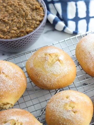 Rolls on a wire rack in front of a dish towel and a bowl of lentil soup