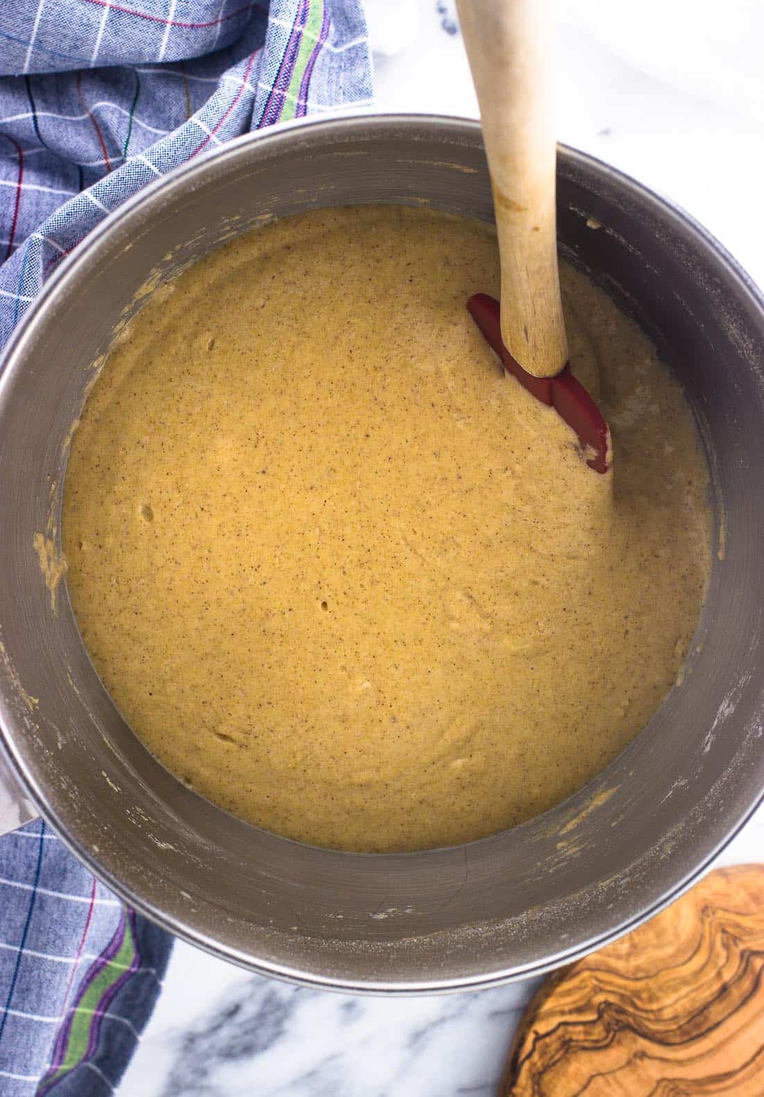 Waffle batter in a metal mixing bowl with a wooden spatula