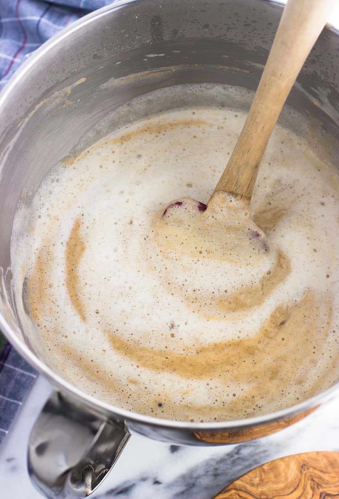 Foamy egg whites being folded into a bowl of waffle batter