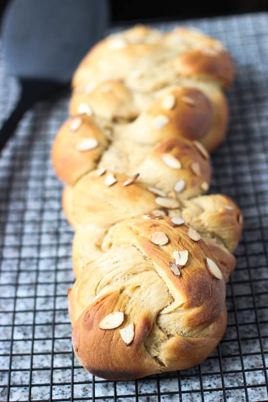 A straight-ahed shot of a full loaf of braided bread on a wire rack next to a big spatula