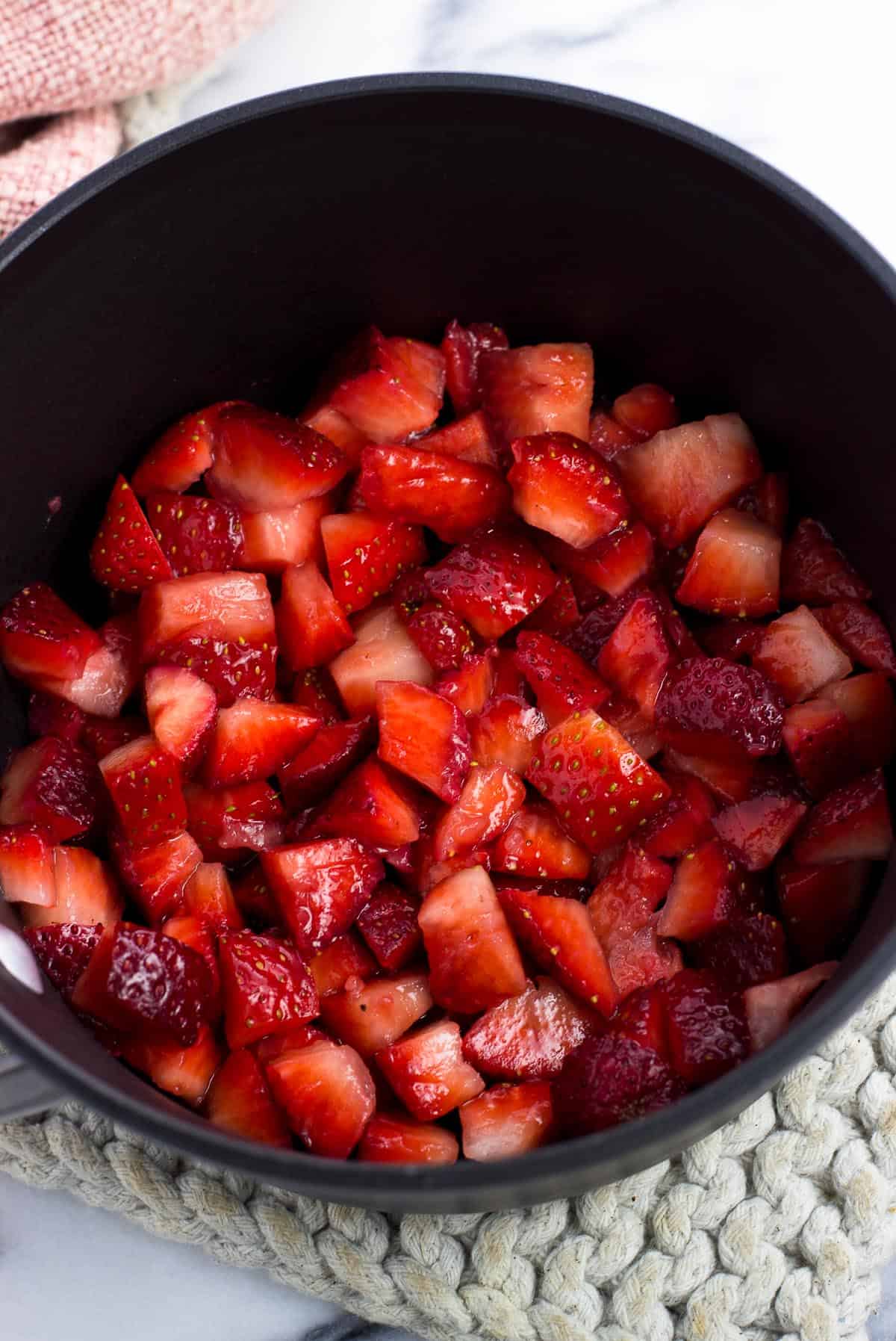 Chopped up strawberries and lemon juice in a saucepan.