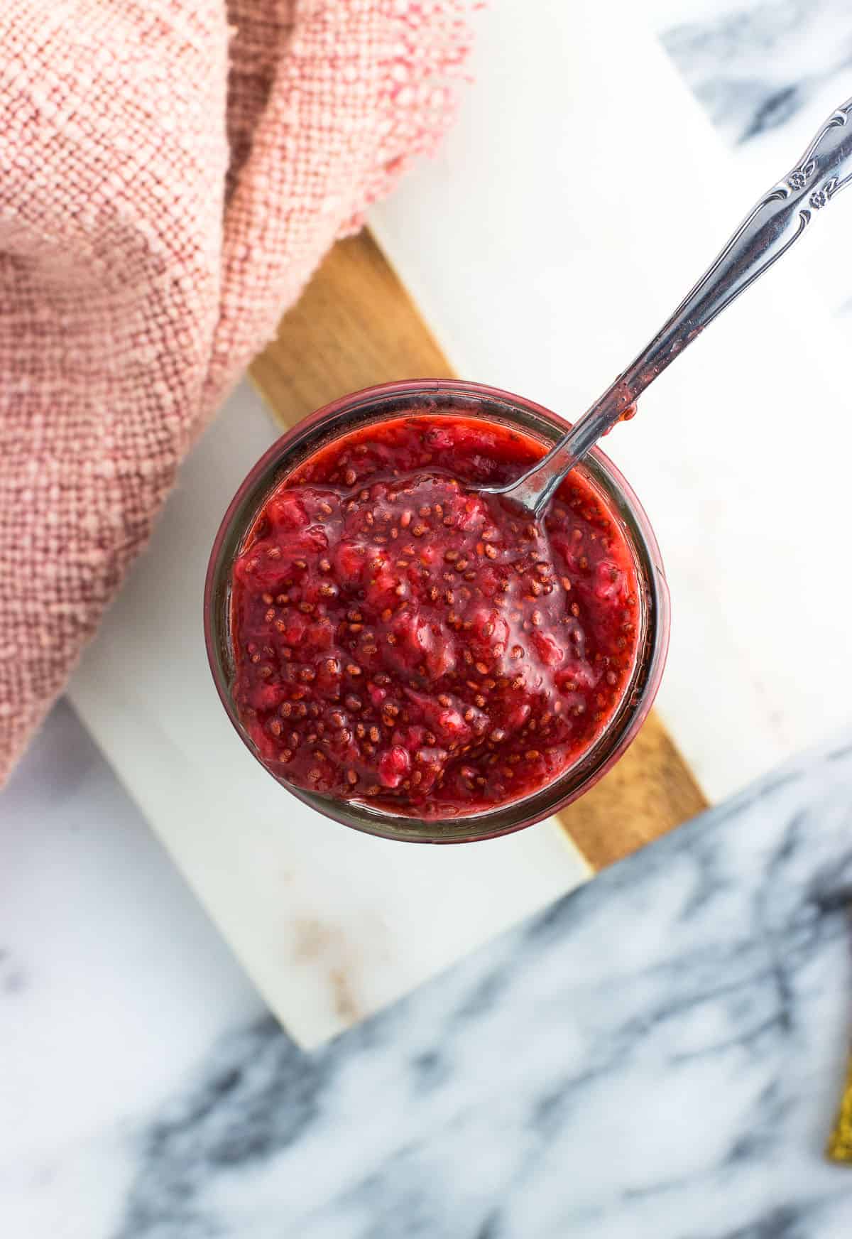 A spoon lifting a scoop of jam out of the jar.