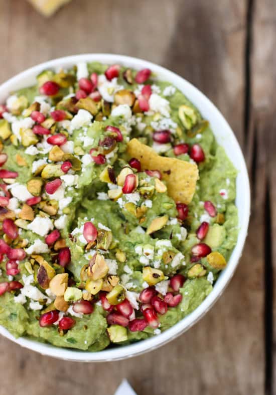 A bowl of guacamole with a chip stuck in it.