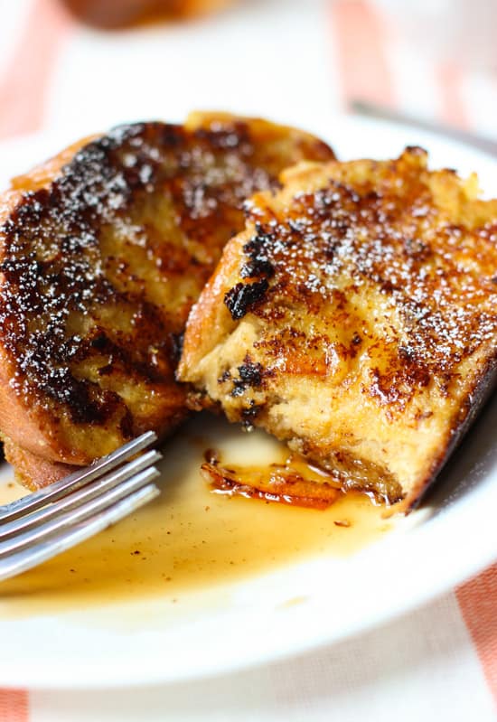 A side view of a section of a half-eaten piece of french toast on a plate.