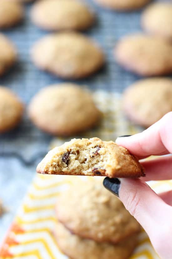 A hand holding up a cookie with a bite taken out of it.