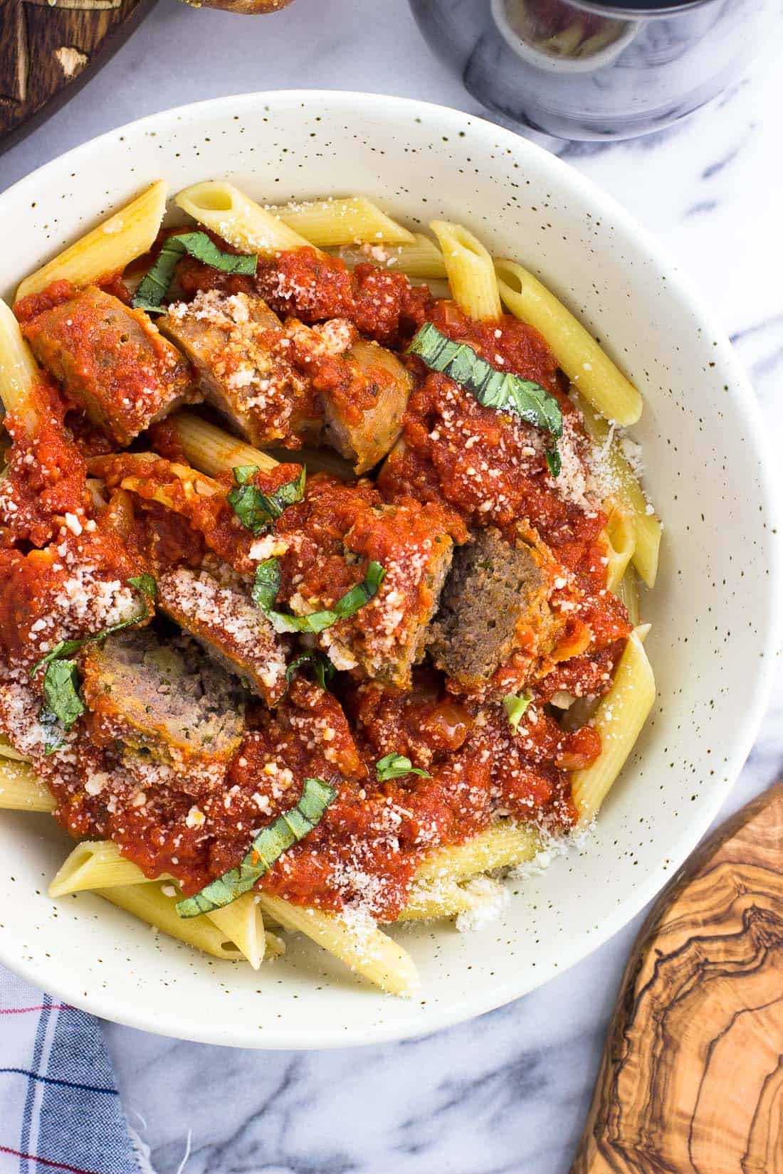 An overhead shot of a bowl of pasta and sauce served with meatballs and sausage