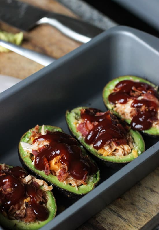 BBQ sauce and cheese on top of pulled chicken in avocado halves.