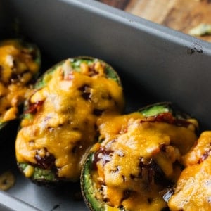 Baked and stuffed avocado boats lined up in a metal loaf pan.