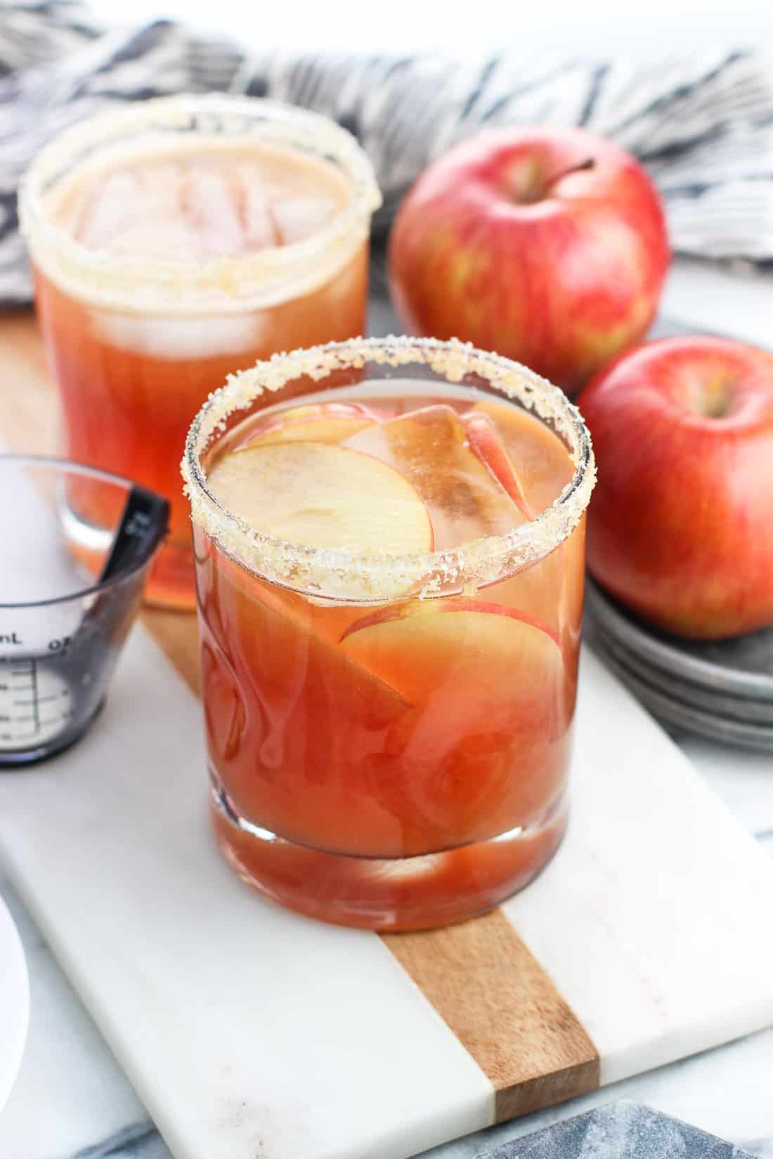 A cranberry apple margarita garnished with a golden sugar rim and apple slices