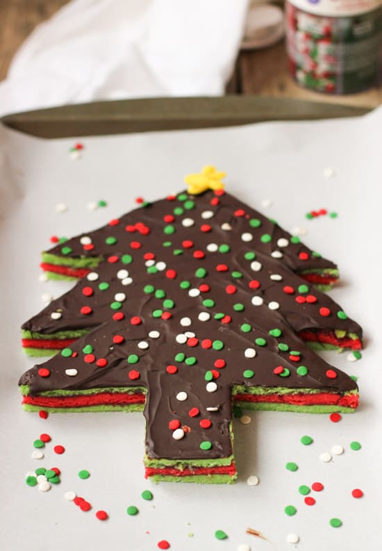 A Christmas tree-shaped rainbow cookie cake on a parchment-lined baking sheet.