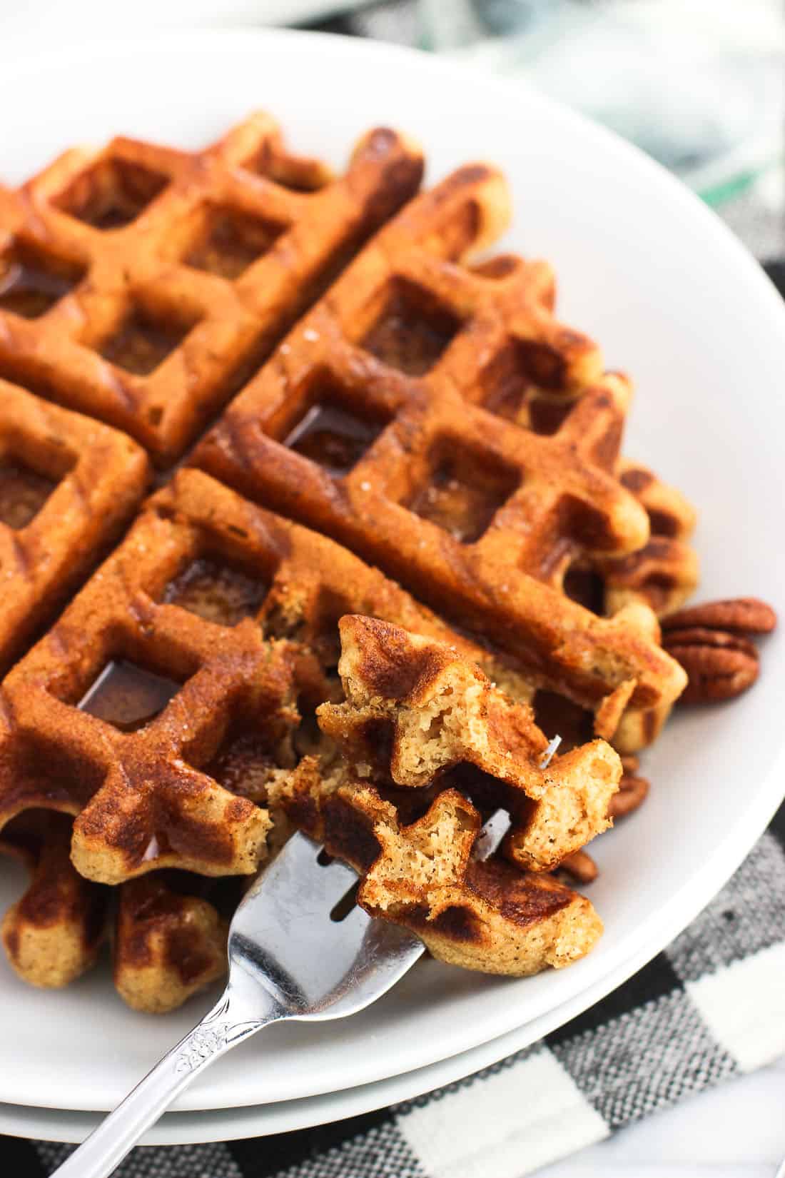 A fork spearing two bites of gingerbread waffles on a plate