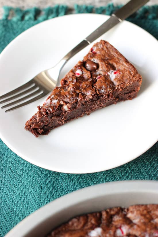 A slice of cookie cake on a dessert plate with a fork.