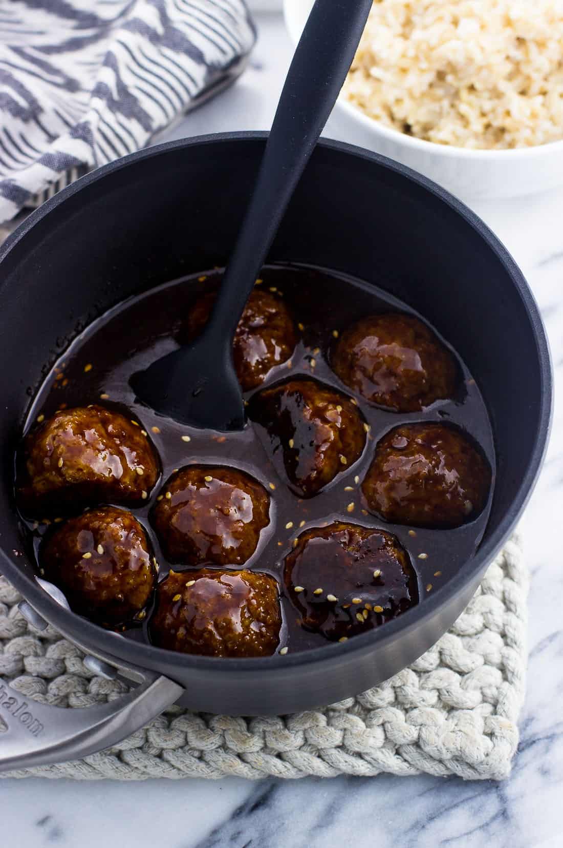 Meatballs in a saucepan covered with hoisin glaze