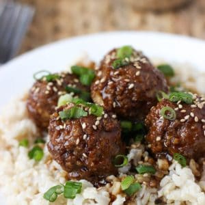 Hoisin meatballs on top of brown rice served on a dinner plate