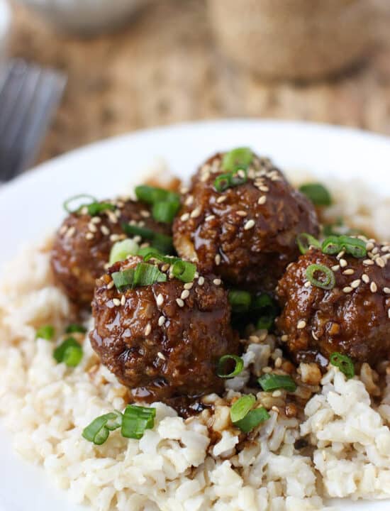 Hoisin meatballs on top of brown rice served on a dinner plate