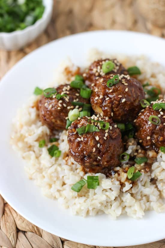 Glazed hoisin meatballs served over brown rice on a dinner plate