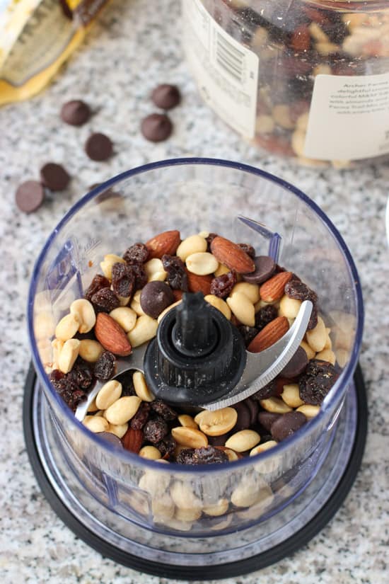 Trail mix in the bowl of a food processor before blending.