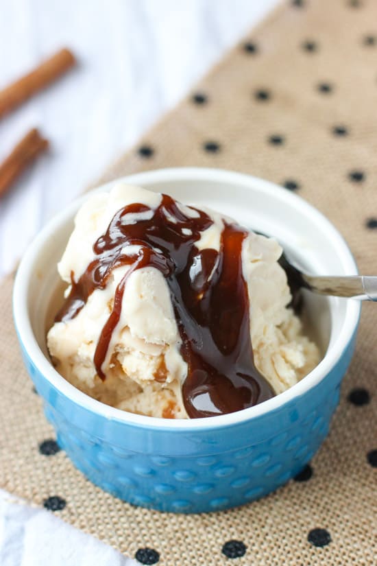 A bowl of ice cream topped with caramel sauce with a spoon.