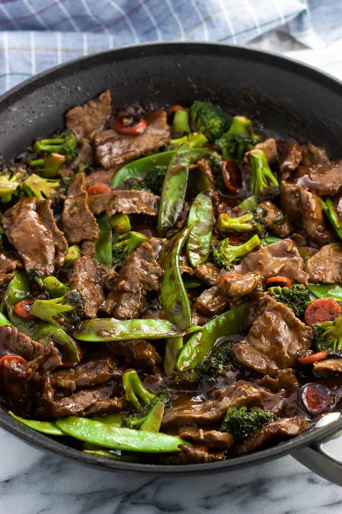 Beef stir fry and mixed vegetables in a skillet with sauce.