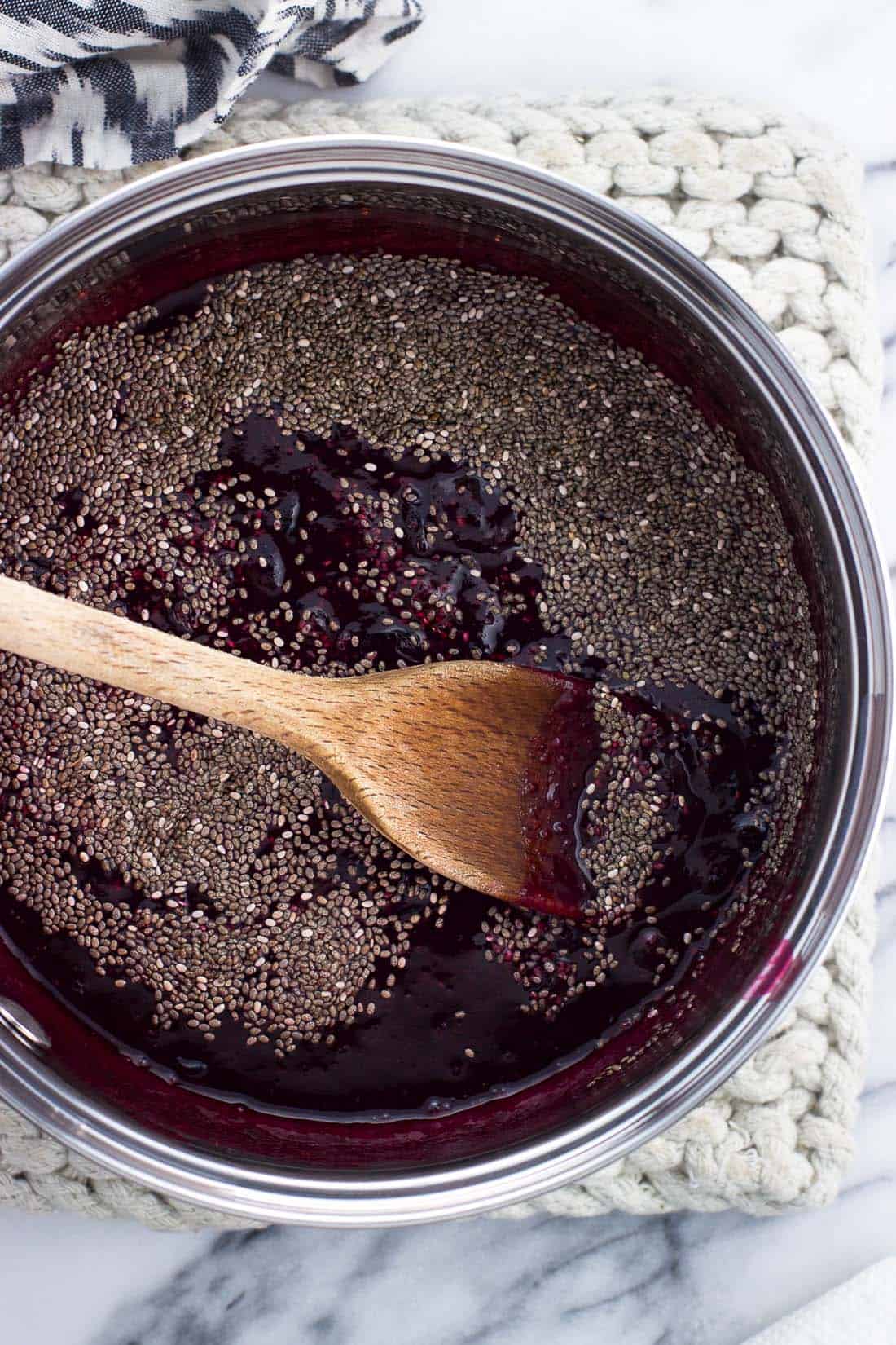 Chia seeds scattered on top of the jam in the saucepan before being stirred in