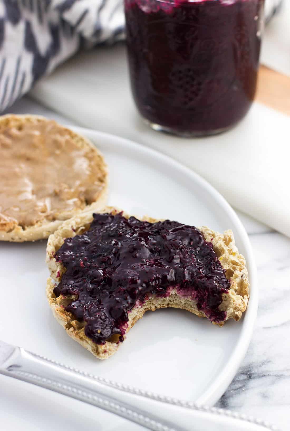 An english muffin spread with peanut butter and jam with a bite taken out of it