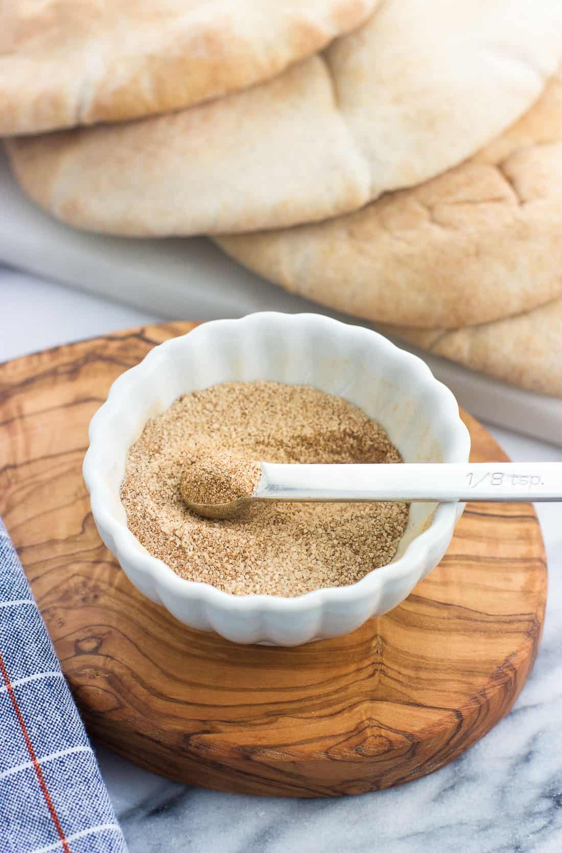 Cinnamon sugar mixed together in a small ceramic bowl with a small measuring spoon dipped in