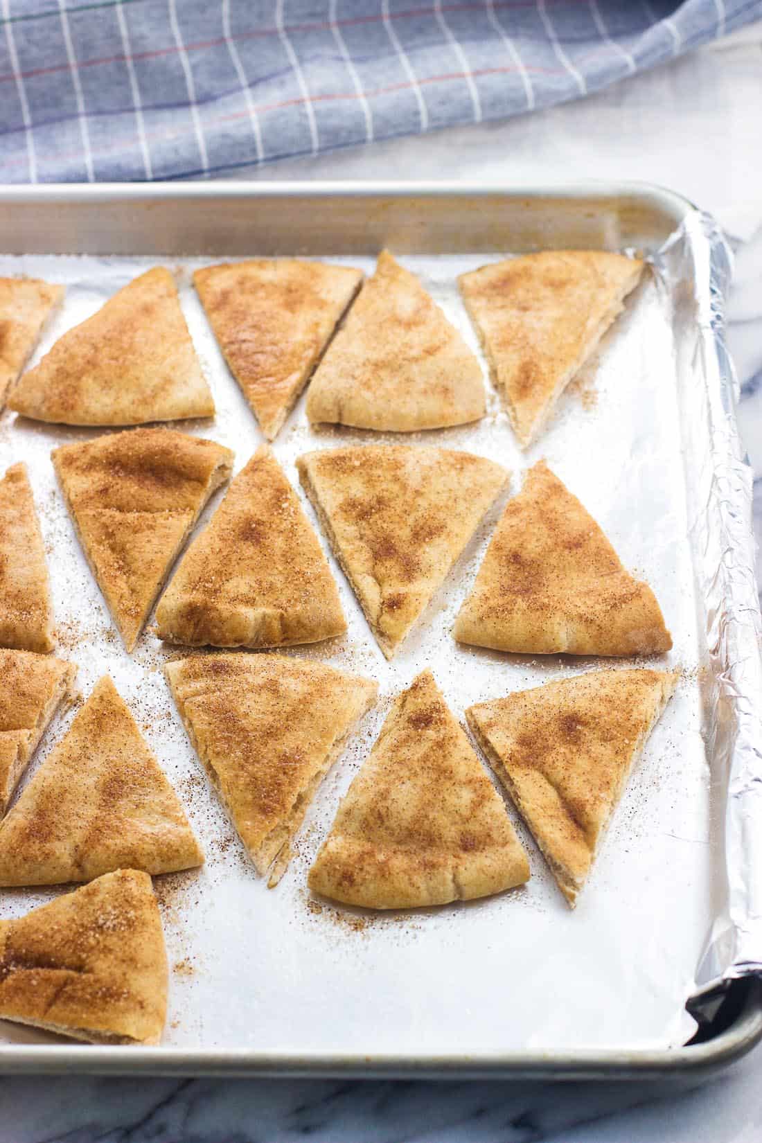 Sliced pita chips on a foil-lined baking sheet pre-bake